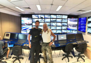 Due colleghi in Control Room davanti alla parete monitoria e alla postazione dei controllori di gara della FOM!